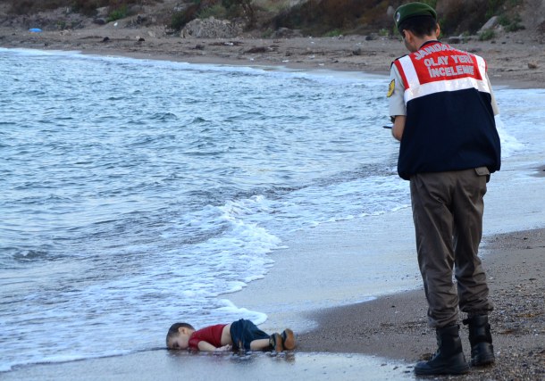 -- AFP PICTURES OF THE YEAR 2015 -- GRAPHIC CONTENT A Turkish police officer stands next to a migrant child's dead body (Aylan Shenu) off the shores in Bodrum, southern Turkey, on September 2, 2015 after a boat carrying refugees sank while reaching the Greek island of Kos. Thousands of refugees and migrants arrived in Athens on September 2, as Greek ministers held talks on the crisis, with Europe struggling to cope with the huge influx fleeing war and repression in the Middle East and Africa. AFP PHOTO / Nilufer Demir / DOGAN NEWS AGENCY = TURKEY OUT =