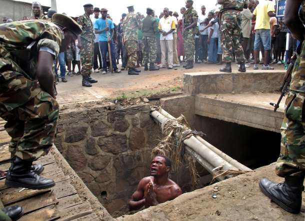 -- AFP PICTURES OF THE YEAR 2015 -- A man begs for help from the military as he stands in a drain where he had hid himself to escape a lynching by a mob at the Cibitoke district of Burundi capital, Bujumbura on May 7, 2015. The man suspected to be an 'Imbonerakure', or member of the Youth League of Burundi's ruling party was finally saved by the army. At least three people were killed in clashes in Burundi in protests over the president's bid for a third term. AFP PHOTO / Aymeric VINCENOT