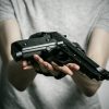 Horror and firearms topic: suicide with a gun on a gray background