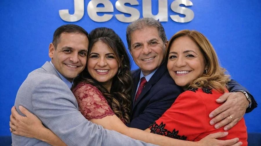 O pastor de terno escuro, cercado pela esposa, nora e filho